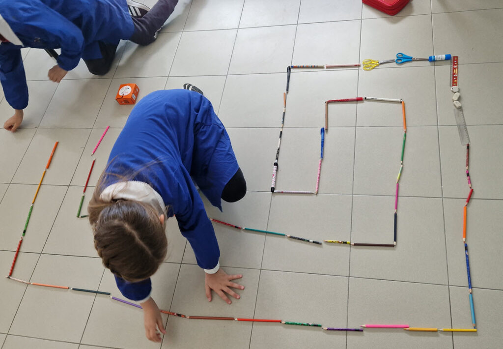 bambini creano un percorso con i loro oggetti scolastici